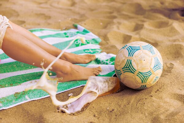 Spilled beer and football on the beach