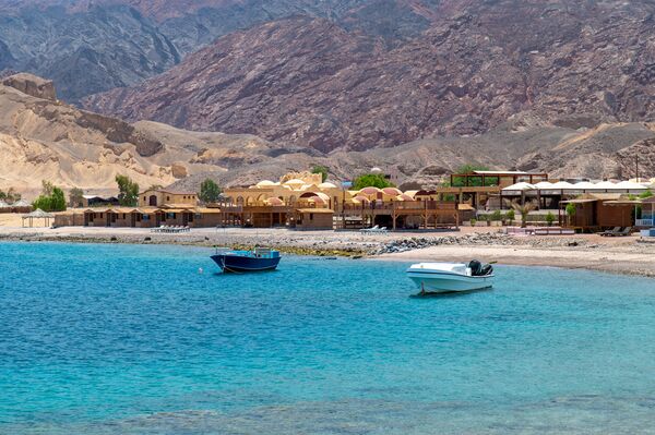 A couple of touristic boats parking at the bay with blue turquoise waters and a mountain in the background