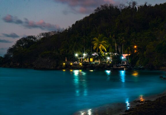 Night-time shot of the sea in Barbados. Hut with twinkling lights.